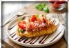 Bruschetta met verse groene pesto roomkaas, mini buffelmozzarella, kerstomaat en prosciutto snippers